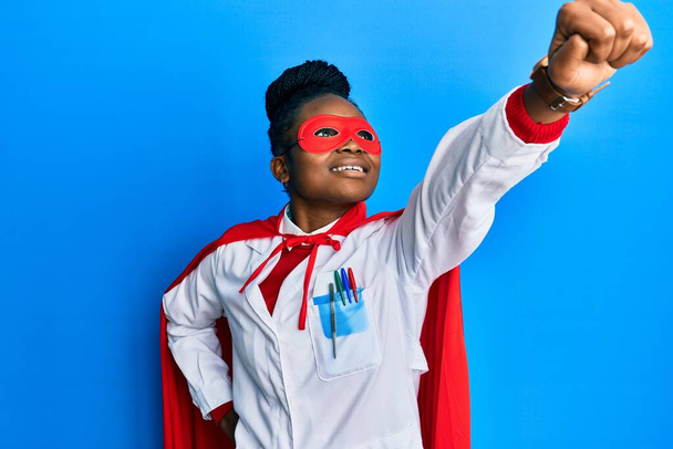 Afro-Amerikaanse dokter vrouw draagt medische jas en super held masker en jas doet macht gebaar - Foto, afbeelding