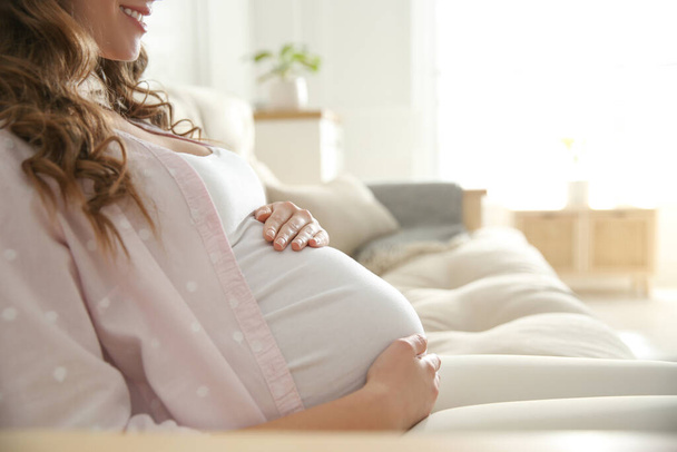 Pregnant woman touching her belly indoors, closeup - Φωτογραφία, εικόνα