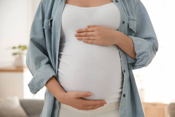 Pregnant woman touching her belly indoors, closeup - Fotoğraf, Görsel