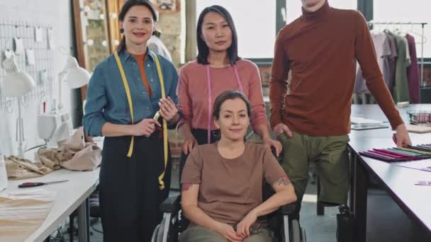 Portret tilt omhoog met traagheid van diverse team van jonge mannelijke en vrouwelijke modeontwerpers poseren voor camera op de werkplek - Video