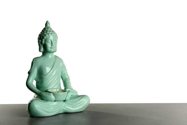 Beautiful ceramic Buddha sculpture with burning candle on table against grey background. Space for text - Fotoğraf, Görsel