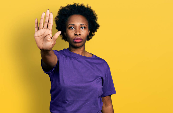 Afrikkalainen amerikkalainen nainen afro hiukset yllään rento violetti t paita tekee lopettaa laulaa kämmenellä. varoittava ilme negatiivisella ja vakavalla eleellä kasvoilla.  - Valokuva, kuva
