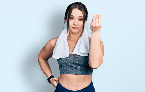Menina hispânica jovem vestindo sportswear e toalha fazendo gesto italiano com mão e dedos expressão confiante  - Foto, Imagem