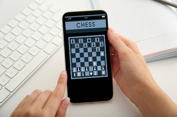 Woman playing online chess on smartphone at table, closeup - Fotografie, Obrázek