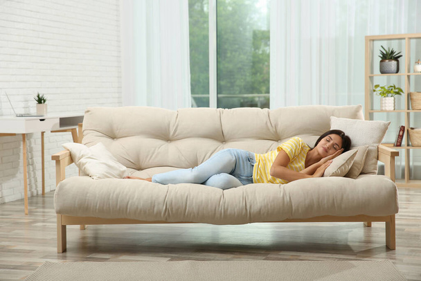 Young woman sleeping on sofa at home - 写真・画像