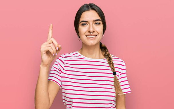 Young hispanic woman wearing casual clothes pointing finger up with successful idea. exited and happy. number one.  - Photo, image