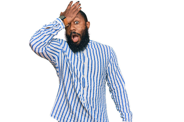 Jonge Afro-Amerikaanse man die een zakelijk shirt draagt verrast met hand op hoofd voor fout, onthoud fout. vergeten, slecht geheugen concept.  - Foto, afbeelding