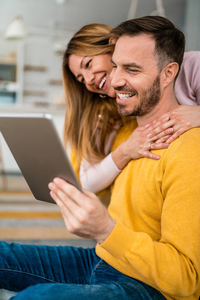 Happy couple spending time with electronic equipment at home - Foto, Imagen