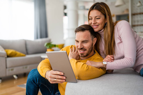 Couple in love hugging and using tablet together at home - Photo, image