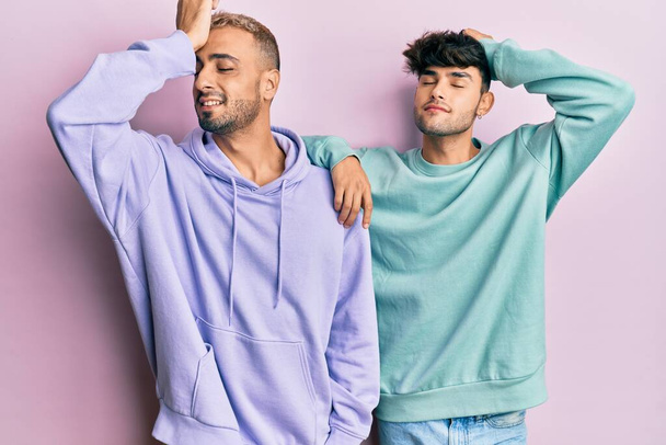 Homosexual gay couple standing together wearing casual clothes smiling confident touching hair with hand up gesture, posing attractive and fashionable  - Photo, Image