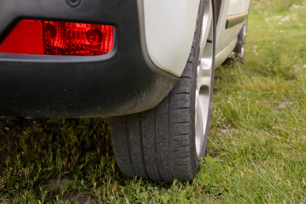 Zblízka pneumatika auta zaparkovaná na zeleném trávníku. Auto nelegálně zaparkované na zelené ploše. - Fotografie, Obrázek