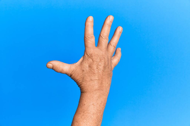 Kéz a vezető spanyol férfi a kék elszigetelt háttér számol 5 mutat öt ujját  - Fotó, kép