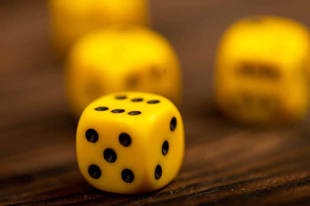 Yellow dice scattered on a wooden table. Close-up, selective focus. An indispensable attribute of board games. - Photo, Image
