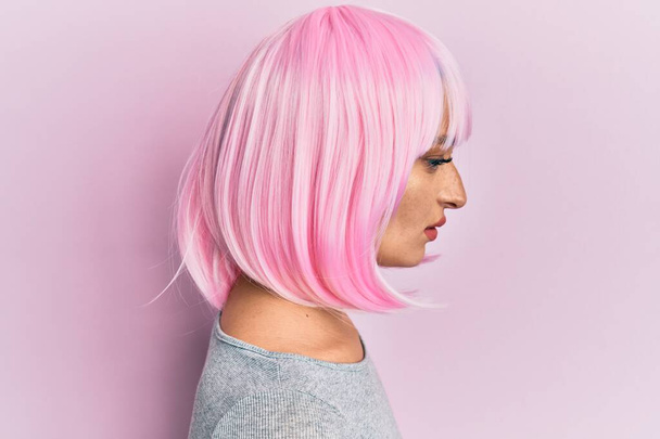 Νεαρή καυκάσια γυναίκα που φοράει ροζ περούκα κοιτάζει προς τα πλάγια, χαλαρώστε προφίλ ποζάρουν με φυσικό πρόσωπο με αυτοπεποίθηση χαμόγελο.  - Φωτογραφία, εικόνα