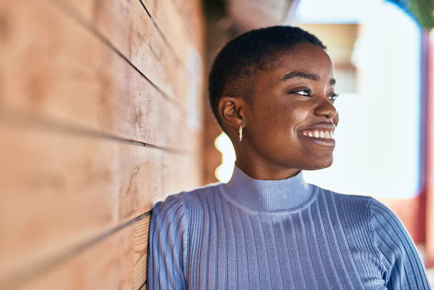 Genç Afrikalı Amerikalı kadın gülümseyerek şehirde mutlu mesut duruyor.. - Fotoğraf, Görsel