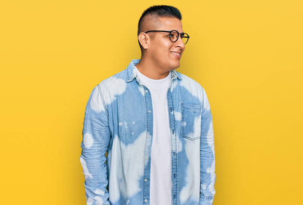 Young latin man wearing casual clothes and glasses looking away to side with smile on face, natural expression. laughing confident.  - Fotografie, Obrázek