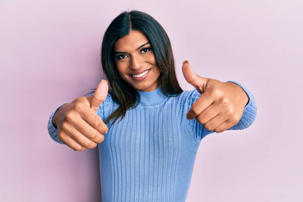 Junge lateinamerikanische transsexuelle Transgender-Frau in lässiger Kleidung, die positive Gesten mit der Hand zustimmt, Daumen hoch lächelnd und glücklich über den Erfolg. Siegergeste.  - Foto, Bild