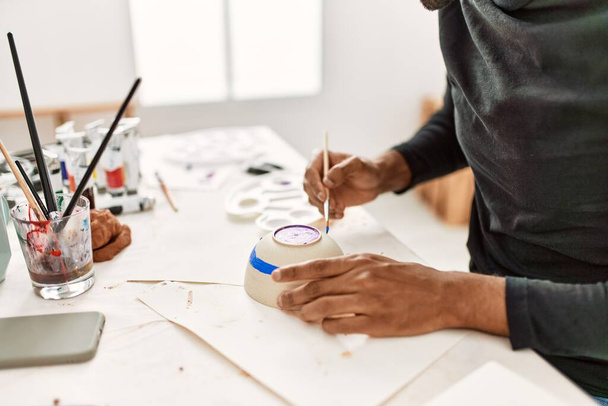 Ręka afrykańskiego amerykańskiego artysty malującego ceramikę w pracowni sztuki. - Zdjęcie, obraz