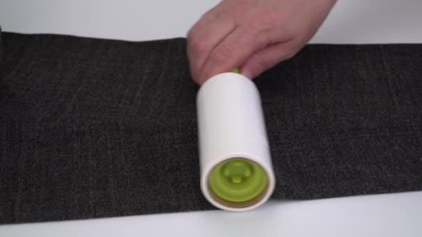 het reinigen van de stof van dierlijk haar met een roller met plakband. kleding verzorging - Video