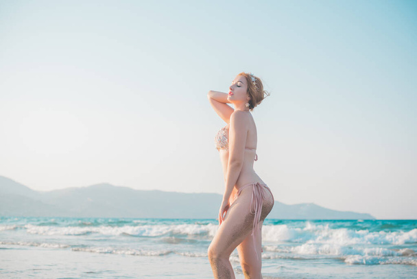 Eurooppalainen nainen, jolla oli täysi mehukas lonkka rannalla rannalla, osoitti hahmonsa uimapuvuissa.  - Valokuva, kuva