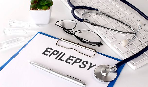 EPILEPSY text on white paper on the white background. stethoscope ,glasses and keyboard - Fotoğraf, Görsel