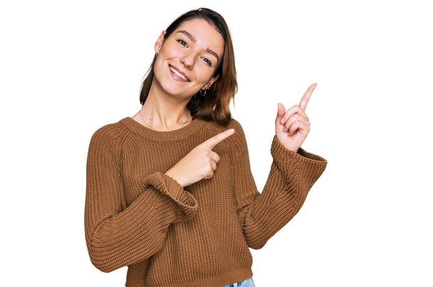 Young caucasian girl wearing casual clothes smiling and looking at the camera pointing with two hands and fingers to the side.  - Photo, Image