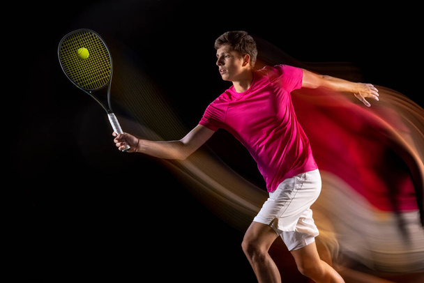 One man, male tennis player training isolated in mixed neon light on dark background. Concept of sport, team competition. - Zdjęcie, obraz