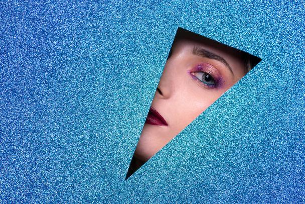 Schöne attraktive blonde junge Frau hellblauen Augen posiert mit blau glänzenden Vordergrund - Studiofotografie von hübschen sinnlichen Mädchen, die in die Kamera schauen - Foto, Bild