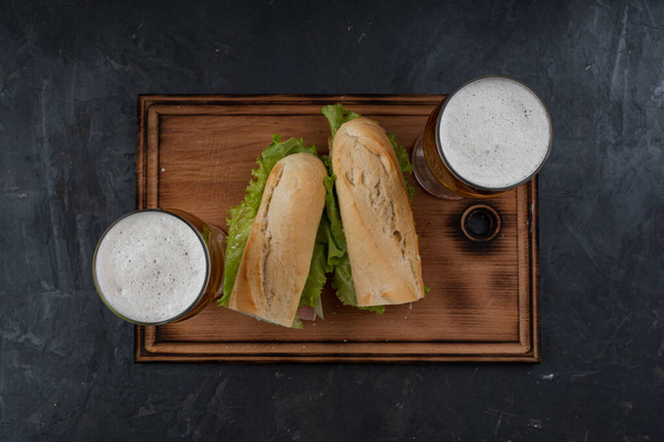 Sandwiches und Bier auf einem Holztisch - Foto, Bild