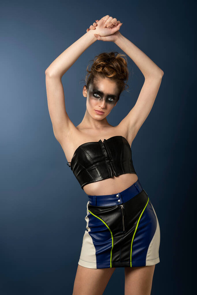 sensual attractive fitness girl with a great body , posing on blue with a striped colored outfit , she has punk dark make up . fashion concept - Foto, Bild