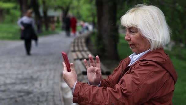 Portraits of woman student using smartphone video conference calling social distance outdoors at the city park - Materiał filmowy, wideo