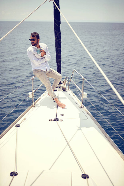 Casual sexy man sailing alone on the yacht; Luxurious lifestyle concept - 写真・画像
