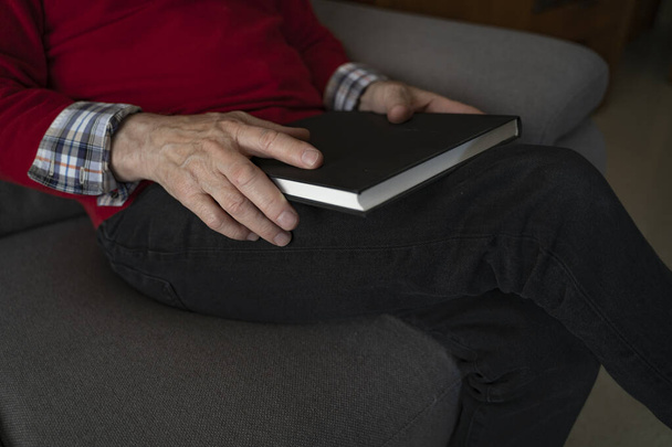 old man reading a book on his sofa - Фото, изображение