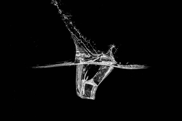 Su, siyah arkaplanda izole edilmiş buz küpleriyle soyut bir şekil alır.. - Fotoğraf, Görsel