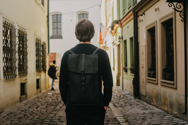 Мужчина путешествует по Европе по улицам старого города с портфелем. Студент путешествует один. Молодой человек - Фото, изображение