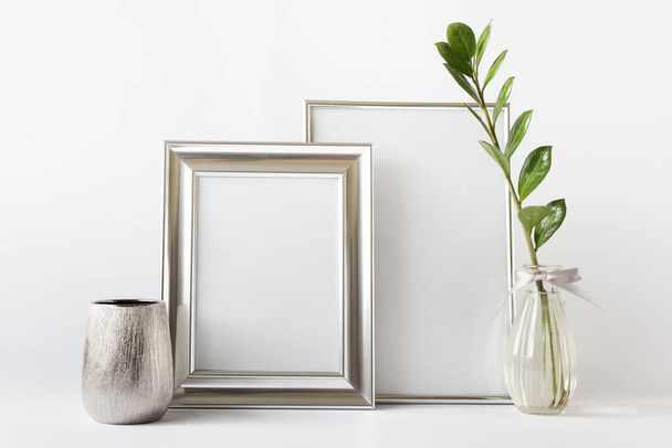 Minimalist stylish composition mockup template with two silver blank frames, zamioculcas plant in glass vase and empty silver pot. - Foto, imagen