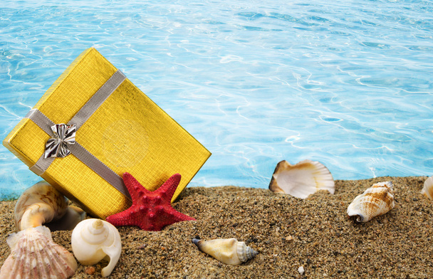 Gold-Geschenk-Box auf Sand mit Sommer Meer Hintergrund  - Foto, Bild