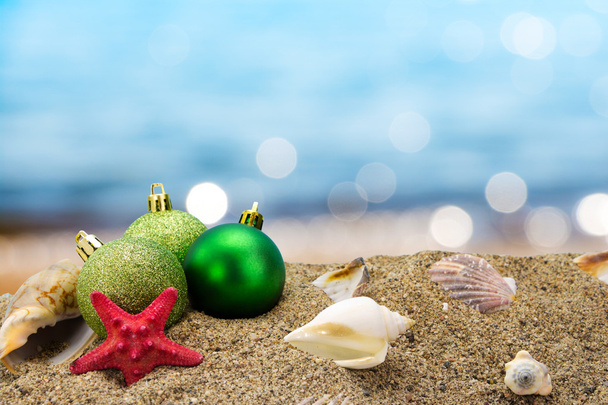 Weihnachtskugel und Muscheln auf Sand mit Sommer Meer Hintergrund  - Φωτογραφία, εικόνα