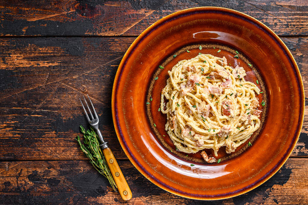 Spaghetti alla carbonara con pancetta, parmigiano duro e crema di salsa. Sfondo in legno scuro. vista dall'alto. Copia spazio - Foto, immagini