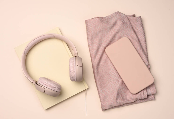 pair of pink sneakers, wireless headphones, a smartphone and a smart watch on a pink background. Things and gadgets for sports, running, flat lay - Photo, Image