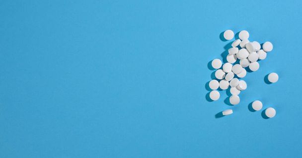 White round pill for healthcare. Medical treatment, blue background, copy space - Fotó, kép