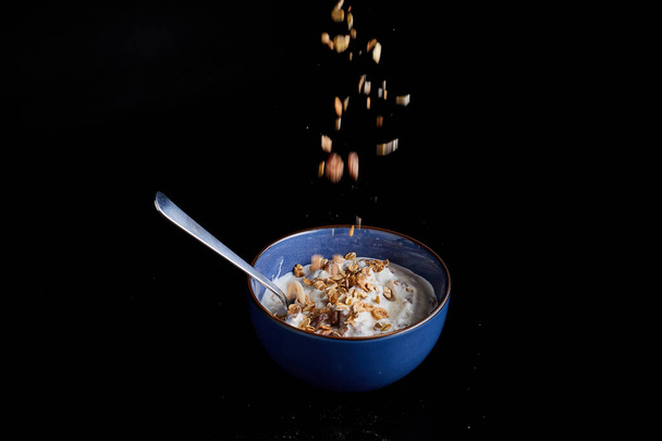 a blue bowl filled with yogurt on a black background - Foto, imagen