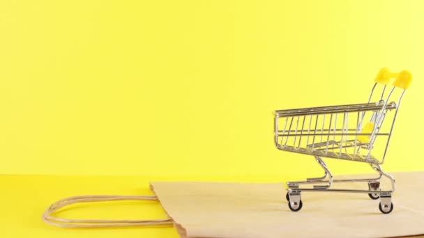 prázdný nákupní vozík na žlutém pozadí, detailní záběr. Černý pátek Nákupní a slevy koncept - Záběry, video