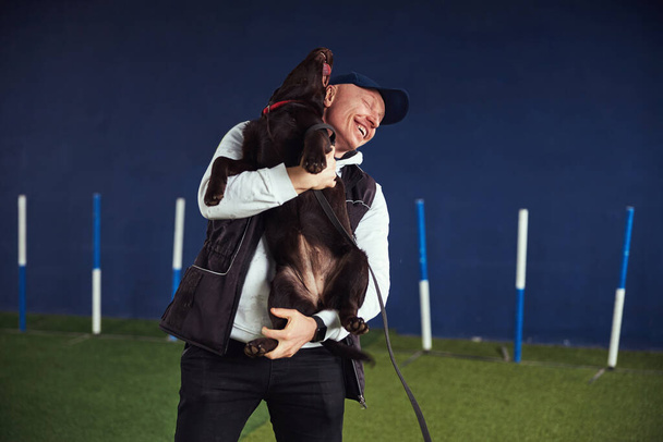 Fröhlicher Instruktor und ein Schoko-Labrador-Retriever im Arm - Foto, Bild