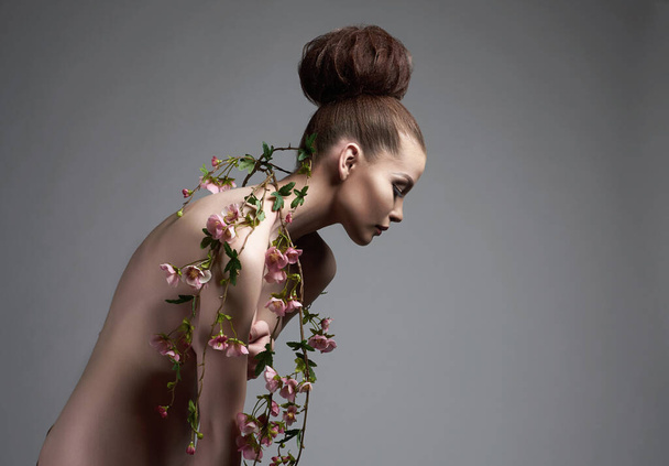 beautiful naked woman like a flower. nude girl with flowers on her body - Фото, изображение