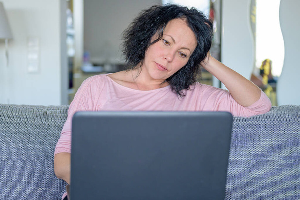 Nachdenkliche Frau arbeitet an ihrem Computer, während sie zu Hause im Büro arbeitet - Foto, Bild