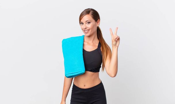 pretty woman smiling and looking happy, gesturing victory or peace. fitness concept - 写真・画像