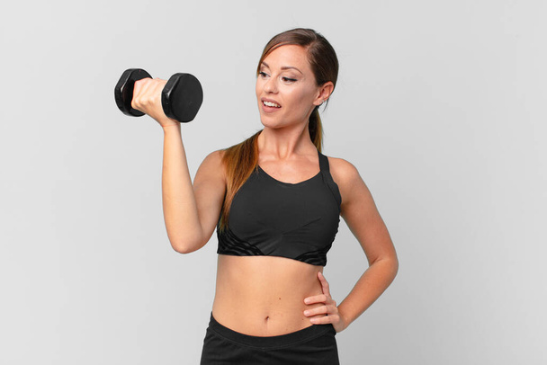 young pretty woman fitness concept and lifting a dumbbell - Photo, Image