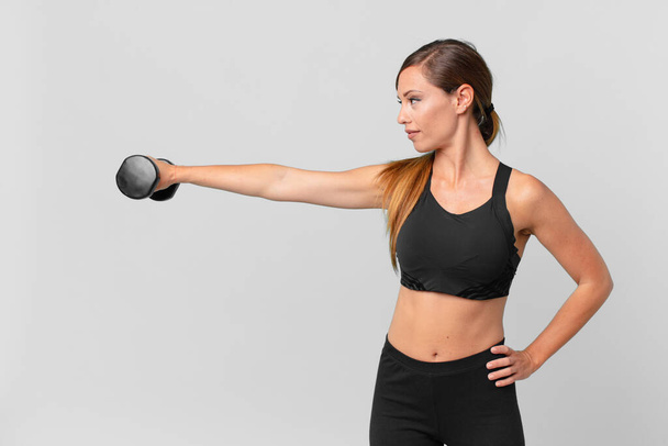 young pretty woman fitness concept and lifting a dumbbell - Photo, image