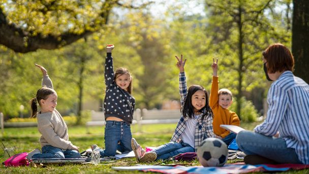 Small children with teacher outdoors in city park, learning group education and art concept. - 写真・画像